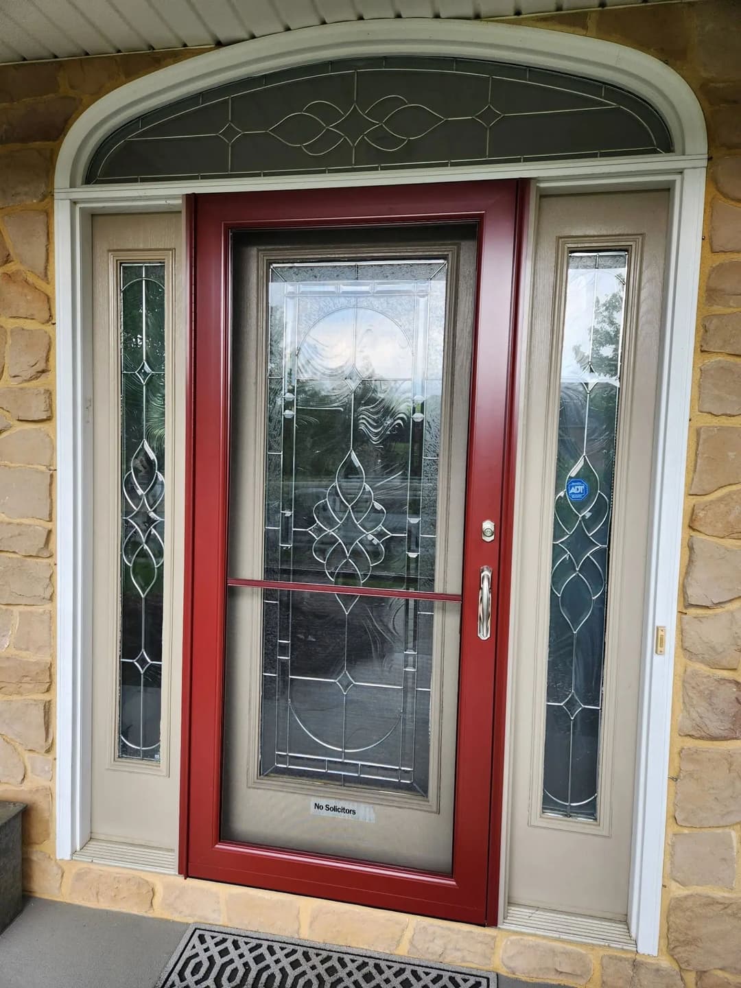 Elegant red front door with decorative glass panels and stone accents. Perfect home entryway.
