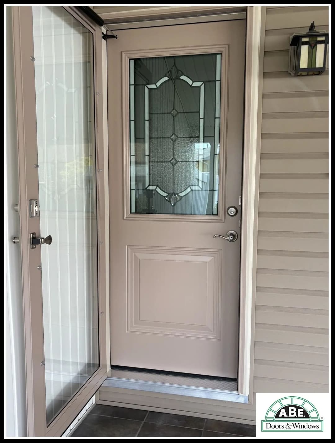 Modern entrance door with decorative glass panel, showcasing ABE Doors & Windows branding.